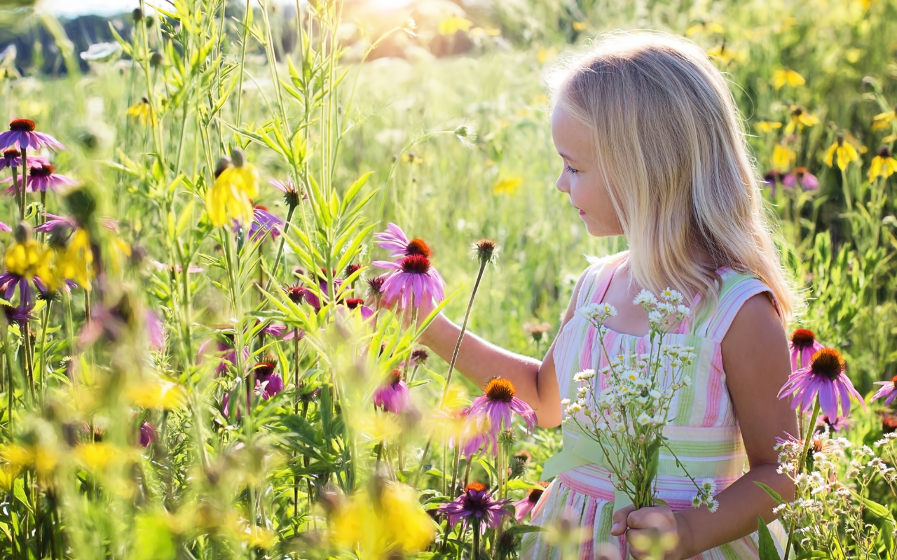 Bambina con capelli biondi in un campo fiorito